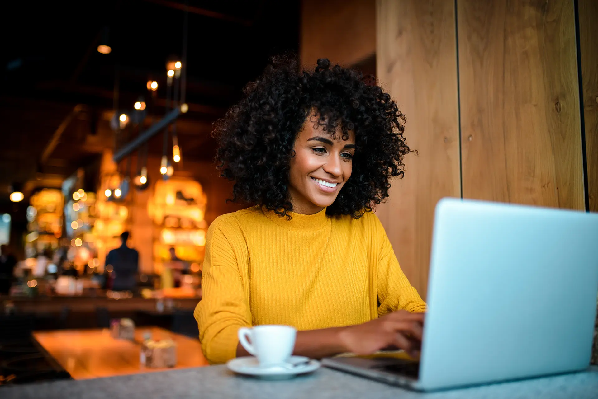 Woman working at a cafe bartop drinking espresso.