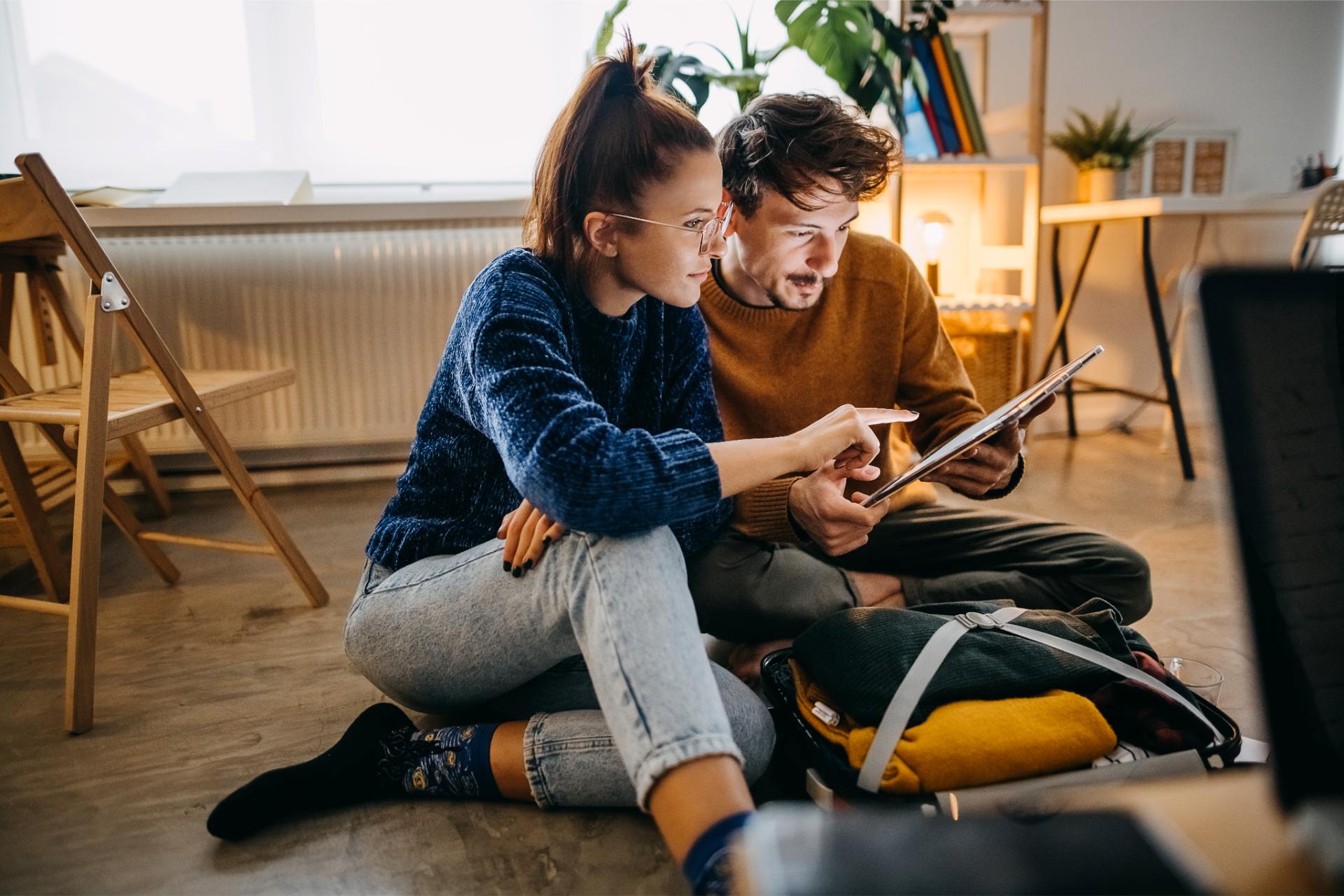 Couple sitting on the floor looking at a tablet.